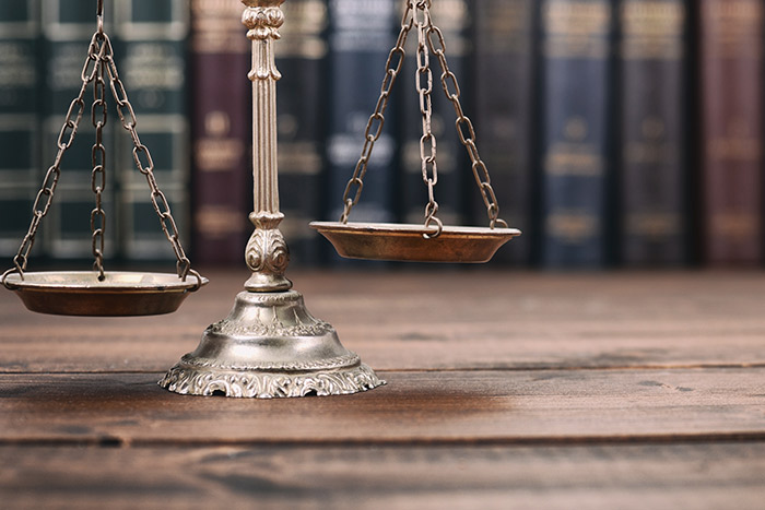 scales of justice and law books on a wooden background